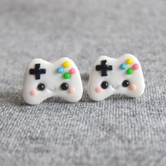 two white video game controllers are sitting on a gray surface and one is painted with multicolored buttons