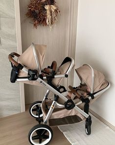 two baby strollers sitting next to each other in front of a door with a wreath hanging on the wall