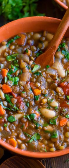 a bowl filled with beans and carrots on top of a wooden table