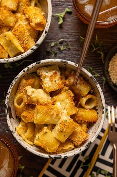 two bowls filled with macaroni and cheese on top of a table next to spoons