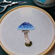 a blue mushroom sitting on top of a table next to some scissors and needle holders