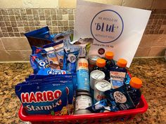 a basket filled with drinks and snacks sitting on top of a counter next to a sign