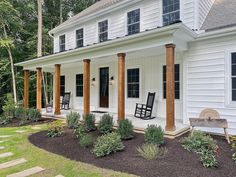 a white house with two rocking chairs on the front porch