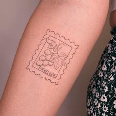 a woman's arm with a stamp on it that has grapes and leaves in it