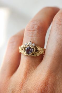 a woman's hand wearing a gold ring with an amethorate and diamond center