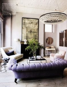 a living room filled with furniture and a chandelier hanging above the couches