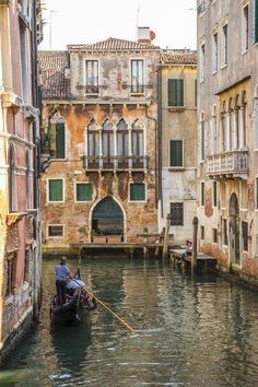 a small boat traveling down a narrow canal between two buildings in the middle of town