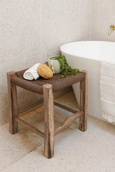 a white bath tub sitting next to a wooden stool