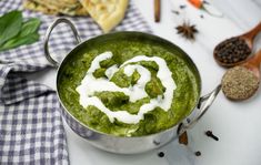 a pot filled with pesto and white sauce on top of a checkered table cloth