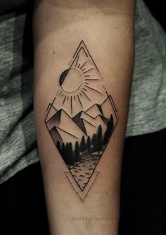 a black and white tattoo on the arm of a person with mountains in the background