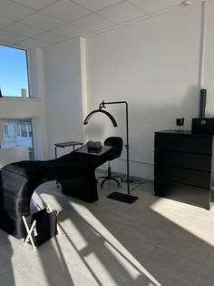 an empty room with black furniture and large windows