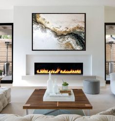 a living room with white furniture and a fire place in the middle of the room