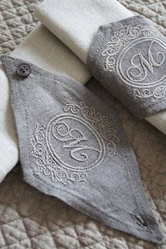 two pieces of cloth with embroidered monograms on them sitting on top of a bed