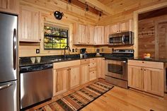 a kitchen with wooden cabinets and stainless steel appliances in the cabin style home that's built into the side of a mountain