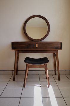 a mirror sitting on top of a wooden table next to a bench and stool in front of it