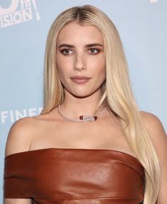 a woman with long blonde hair wearing a brown leather dress and choker on her neck