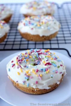 a white plate topped with frosted donuts covered in sprinkles