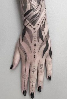 a woman's hand with black and white tattoos on her left arm, holding onto the