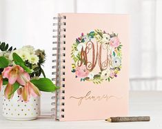 a pink notebook with the word mom written on it next to a potted plant