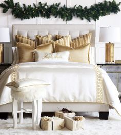 a white bed topped with lots of pillows next to a night stand and christmas decorations