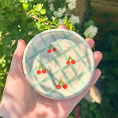 a hand holding a bowl with cherries painted on it