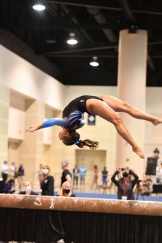 a woman is doing a trick on the balance beam