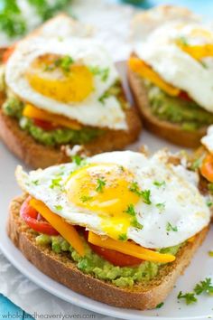 eggs are on top of toast with avocado, tomatoes and peppers in the middle