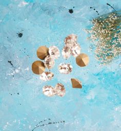 several pieces of gold and clear glass sitting on top of a blue surface next to a plant