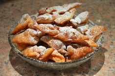 powdered sugar coated pastries in a glass bowl on a granite countertop, ready to be eaten