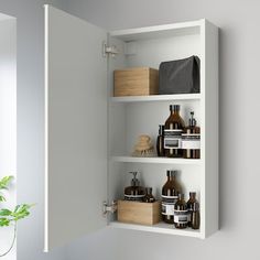 a white shelf filled with lots of different types of bathroom items next to a potted plant