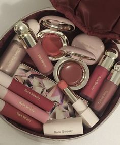 the contents of a purse are neatly arranged in a round container, including lip glosses and lipstick