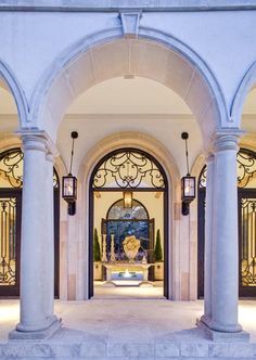 the entrance to an elegant mansion with columns and lights on either side of the entryway