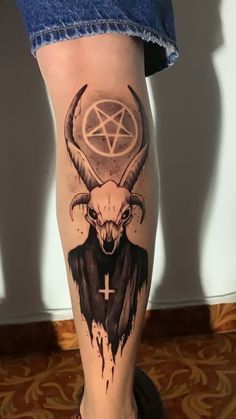 a woman's leg with a tattoo on it that has an animal head and pentagram