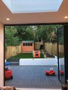 the view from inside a house looking out onto a backyard with toys on the deck