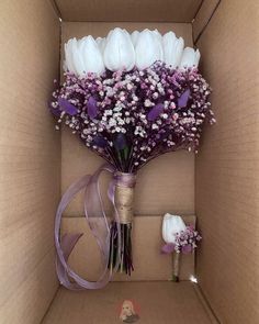 a bouquet of white and purple flowers in a cardboard box