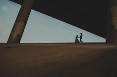 two people are walking on the side of a building