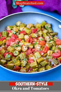 a pan filled with okra and tomatoes on top of a blue tablecloth next to a purple towel