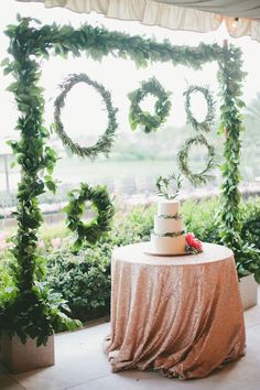 a wedding cake on top of a table with greenery