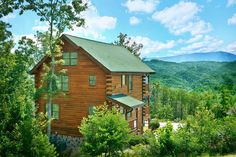 a log cabin nestled in the woods with mountains in the backgrouds and trees on either side