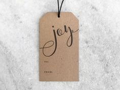 a brown tag with the word joy on it hanging from a string attached to a marble surface