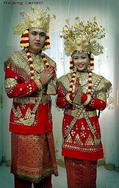 two people dressed in red and gold standing next to each other with their hands together