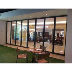 an empty patio with tables and chairs in front of glass doors