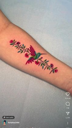 a small tattoo on the arm of a woman with flowers and hummings in it