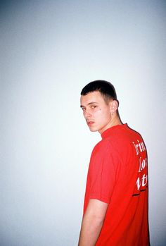 a young man in a red shirt is posing for the camera