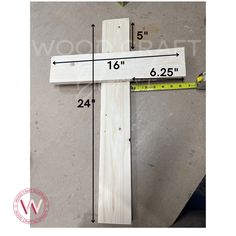 a wooden cross sitting on top of a floor next to a measuring tape and ruler