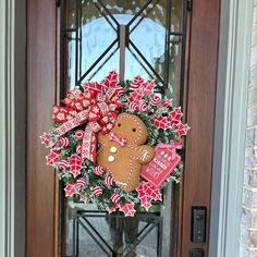 a christmas wreath decorated with gingerbreads and candy canes on a front door