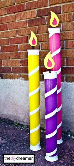 three brightly colored candles sitting next to a brick wall