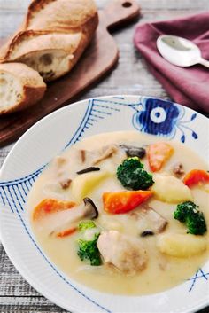 a bowl of soup with broccoli, carrots and meat on a plate