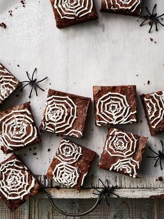 chocolate brownies with white frosting and spider webs on top, sitting on a table