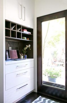 a black and white door is open to a room with shelves, drawers, and a rug on the floor